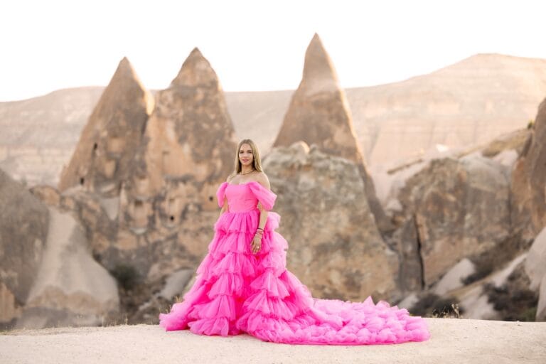 Hollywood actress in a pink Barbie-style dress posing in front of Cappadocia rock formations