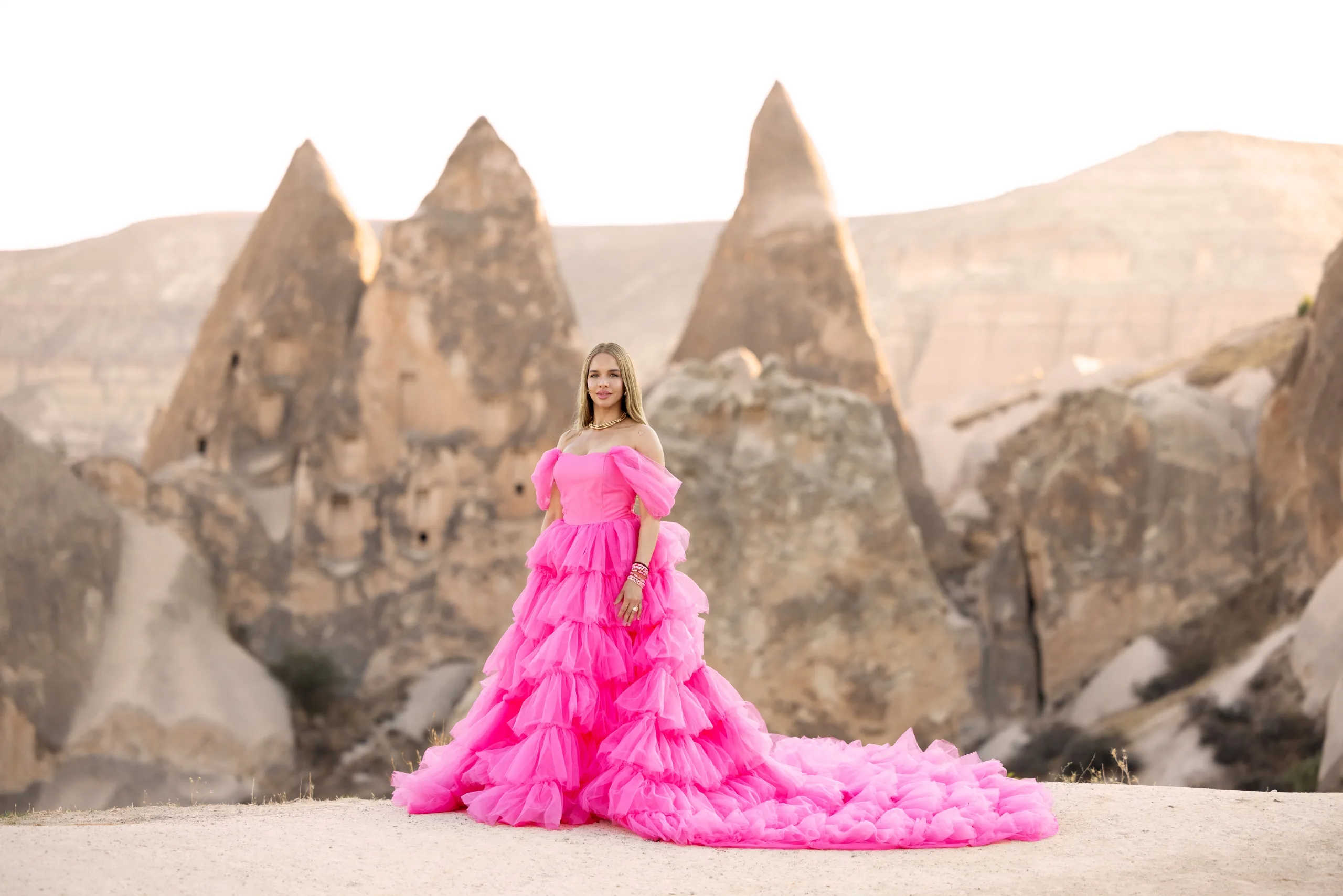 Hollywood actress in a pink Barbie-style dress posing in front of Cappadocia rock formations