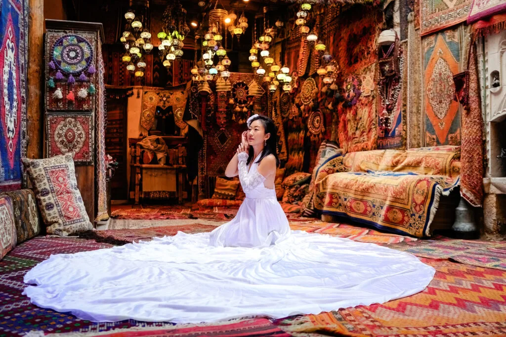 Woman in a white dress sitting in a colorful carpet gallery in Cappadocia