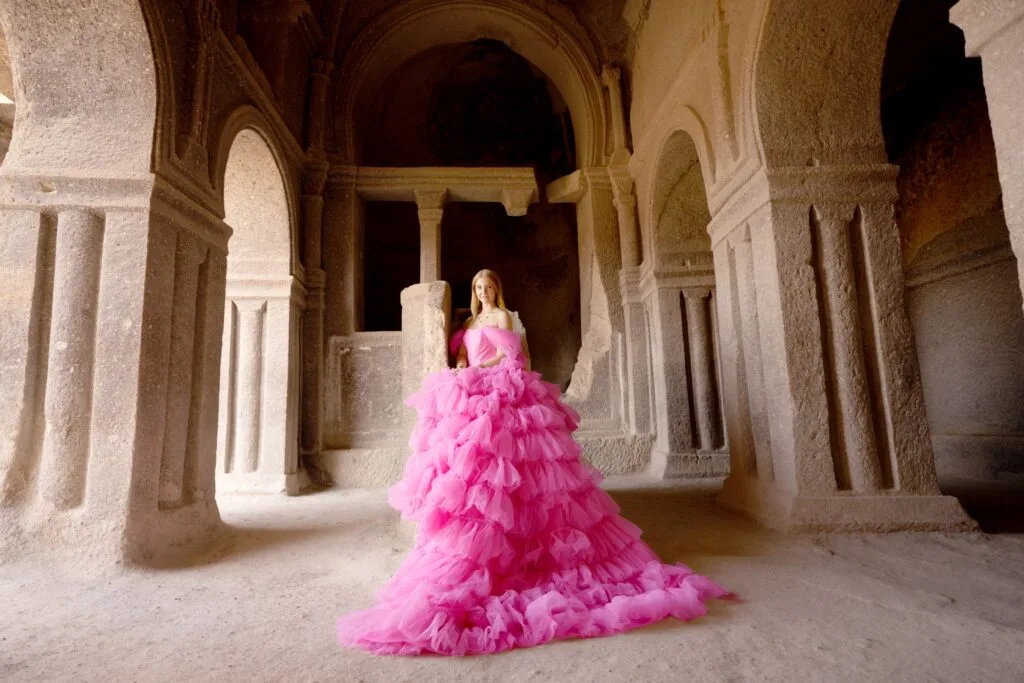 Woman in a pink dress standing inside an old stone church in Cappadocia